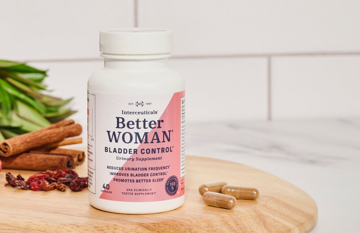 BetterWOMAN natural bladder control supplement bottle with capsules and herbal ingredients on a wooden board.