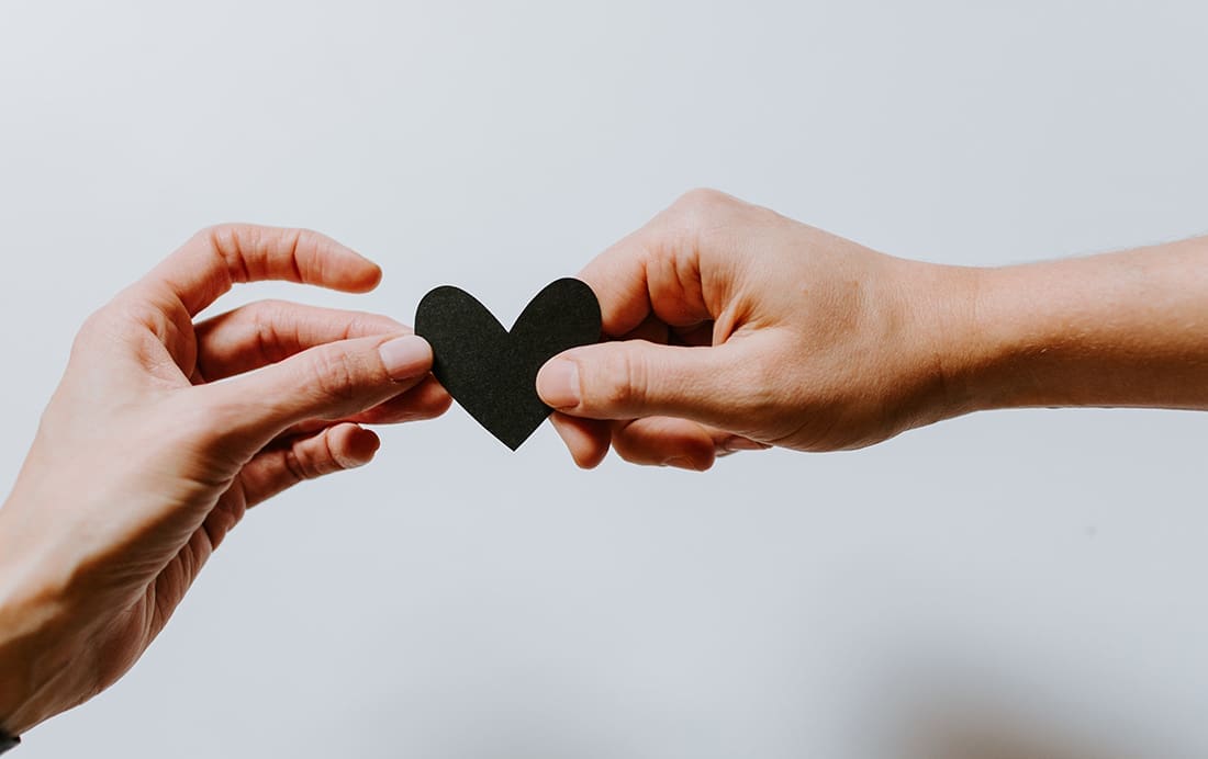 Two hands holding a heart shaped paper