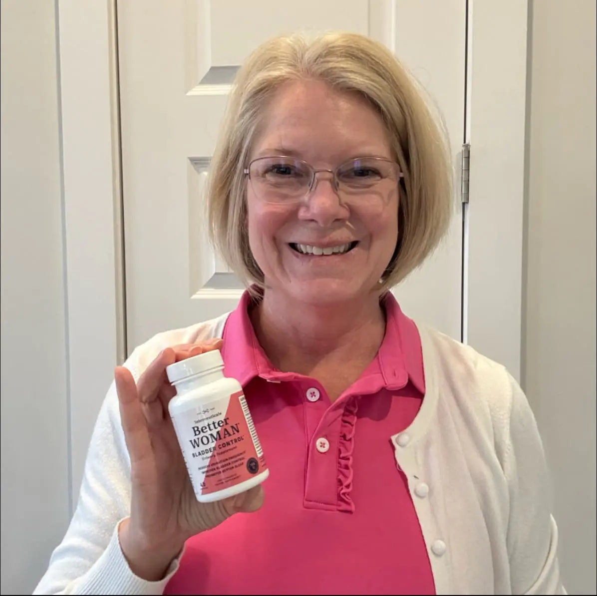 A smiling woman holding a bottle of Interceuticals Better Woman Bladder Control, a supplement designed to support urinary health and sleep quality.