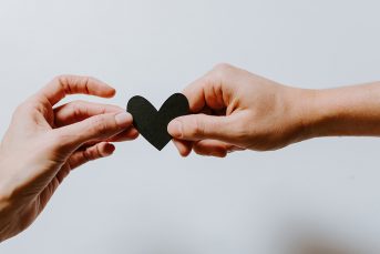 Two hands holding a heart shaped paper